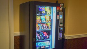 Een automaat in een kamer met een kamerbreed tapijt en gele wanden.
