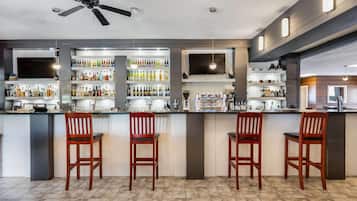 A bar area with a ceiling fan, shelves of bottles, and bar stools.