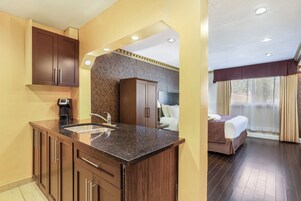 Habitación de hotel con kitchenette, cama y baño.