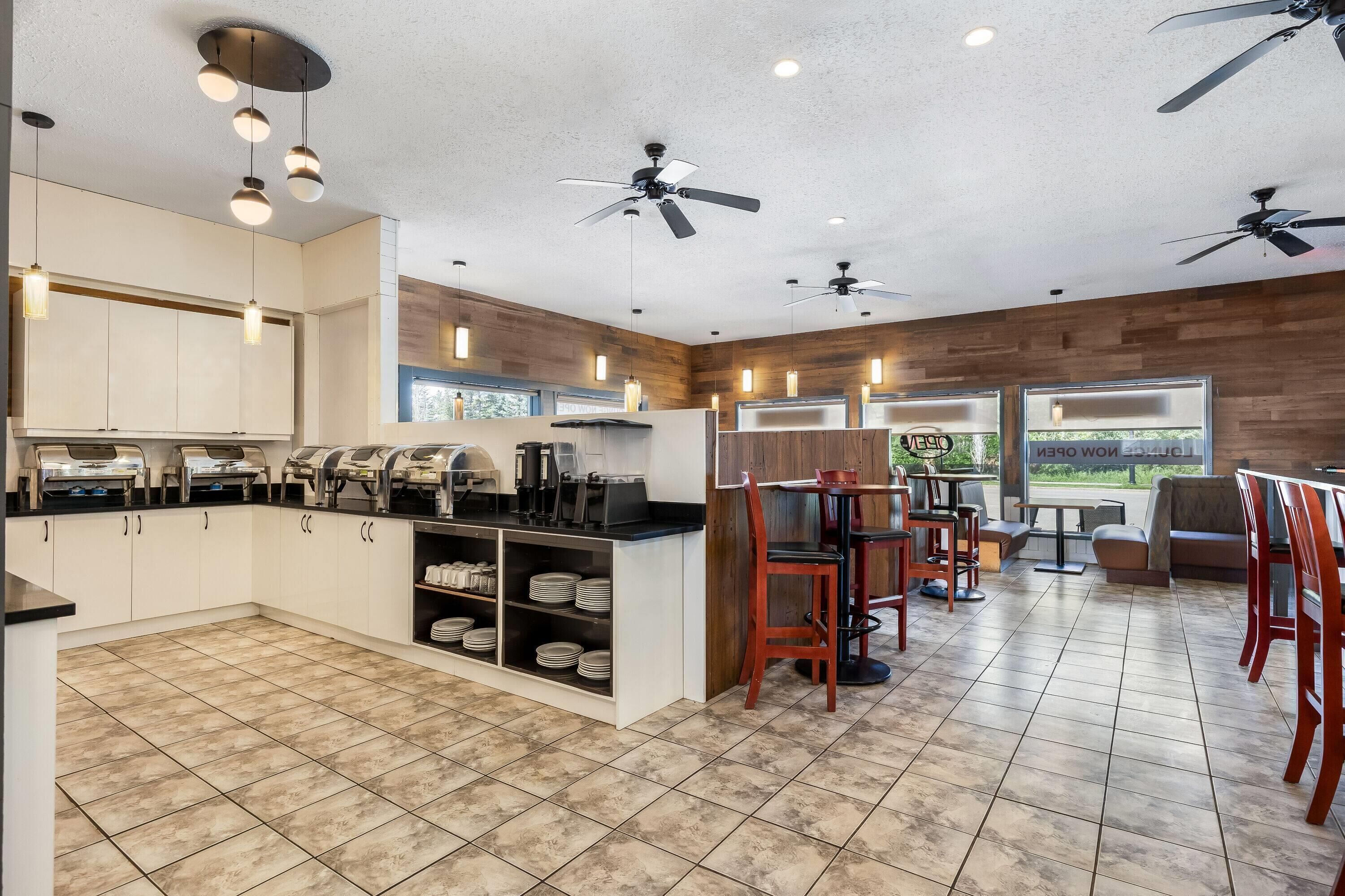 A modern kitchen with a central island, built-in appliances, and a dining area with wooden tables and chairs.