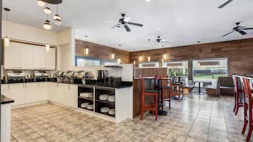 Cocina moderna con una isla central, electrodomésticos integrados y un comedor con mesas y sillas de madera.