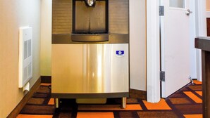 A hallway with a water dispenser, a door, and patterned carpet. - Days Inn by Wyndham Sylvan Lake (Sylvan Lake)