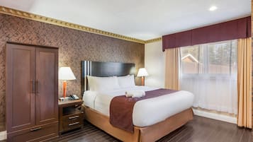 Une chambre d’hôtel avec un lit, des lampes de chevet, une armoire et une fenêtre avec des rideaux.