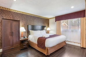 Une chambre d’hôtel avec un lit, des lampes de chevet, une armoire et une fenêtre avec des rideaux.