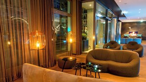 A modern lounge with a sofa, armchairs, and a coffee table. - Motel One München-Olympia Gate (Munich)