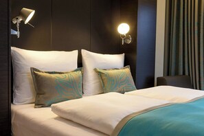 A hotel room with a bed, two bedside lamps, a chair, and a curtain. - Motel One München-Olympia Gate (Munich)