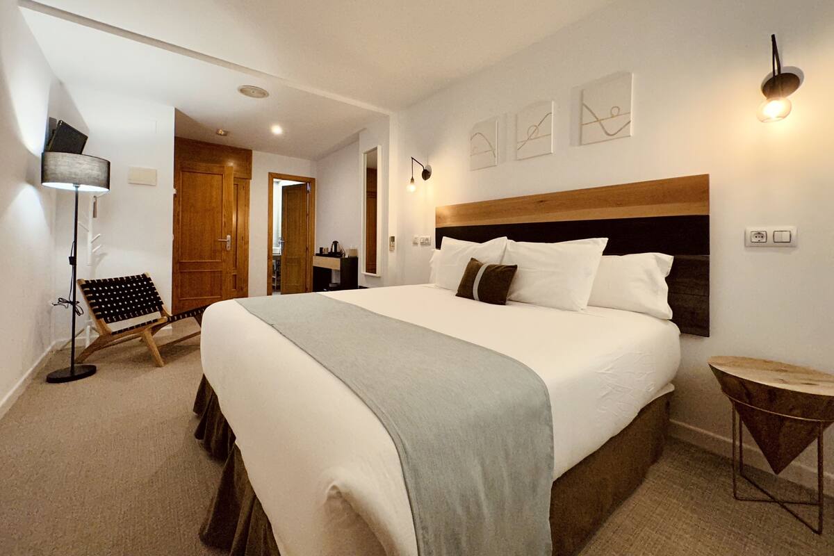 A modern hotel room with a large bed, a desk, and a chair.