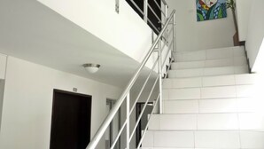 A staircase with white railings and white tiles, leading to a dark door marked with the number 203. - Apartasuites San Marcos (Cali)