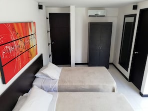 A modern hotel room with two beds, a large abstract painting, and a wardrobe. - Apartasuites San Marcos (Cali)