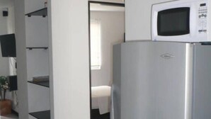 A modern kitchen with a stainless steel refrigerator, a microwave, and white cabinetry. - Apartasuites San Marcos (Cali)