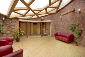 Relax in a spacious room with a high ceiling, brick wall, and comfortable seating area.