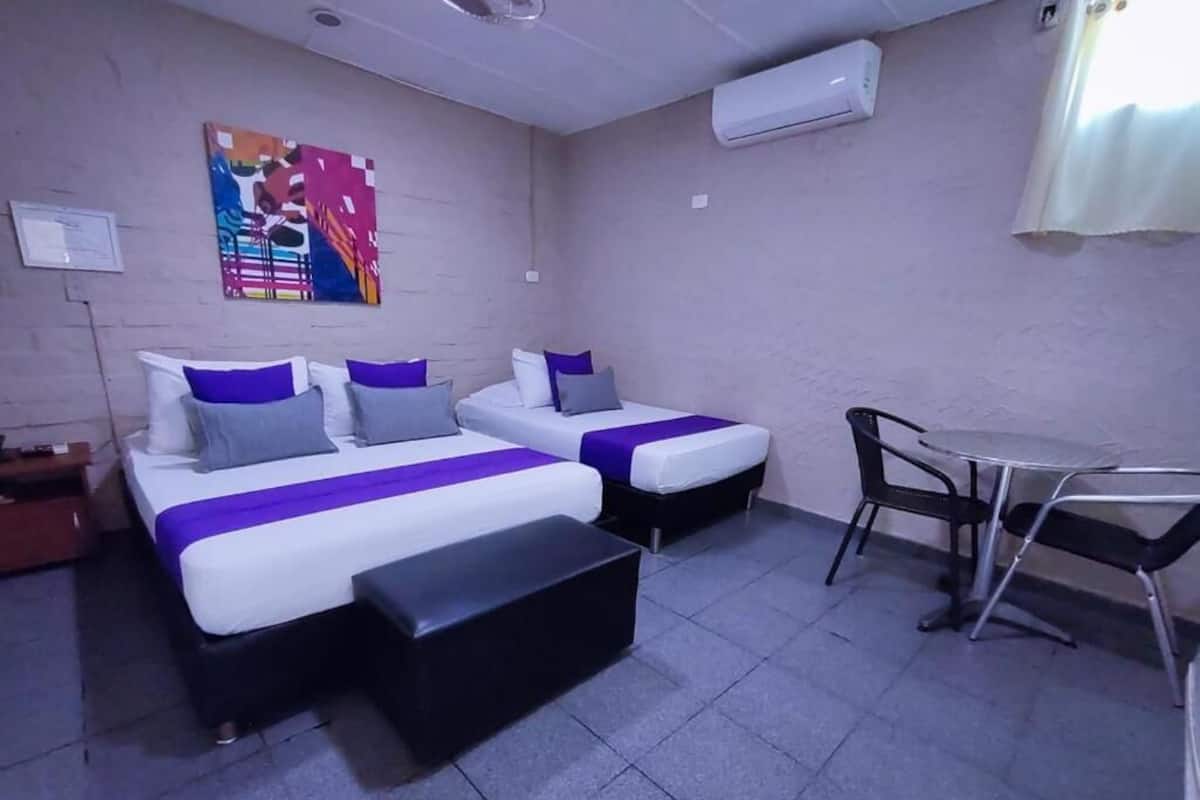 A hotel room with two beds, a small table, and a chair.