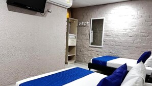 A hotel room with two beds, a wardrobe, a mirror, and an air conditioning unit. - Casa Boston Inn (Barranquilla)