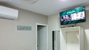 A room with a television displaying 'The Buccaneers' on the wall, a white cabinet with a mirror, and a door leading to another room. - Casa Boston Inn (Barranquilla)