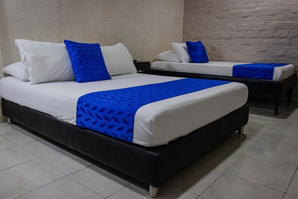 Dos camas con ropa de cama blanca y azul, un marco negro y una pared blanca con textura.
