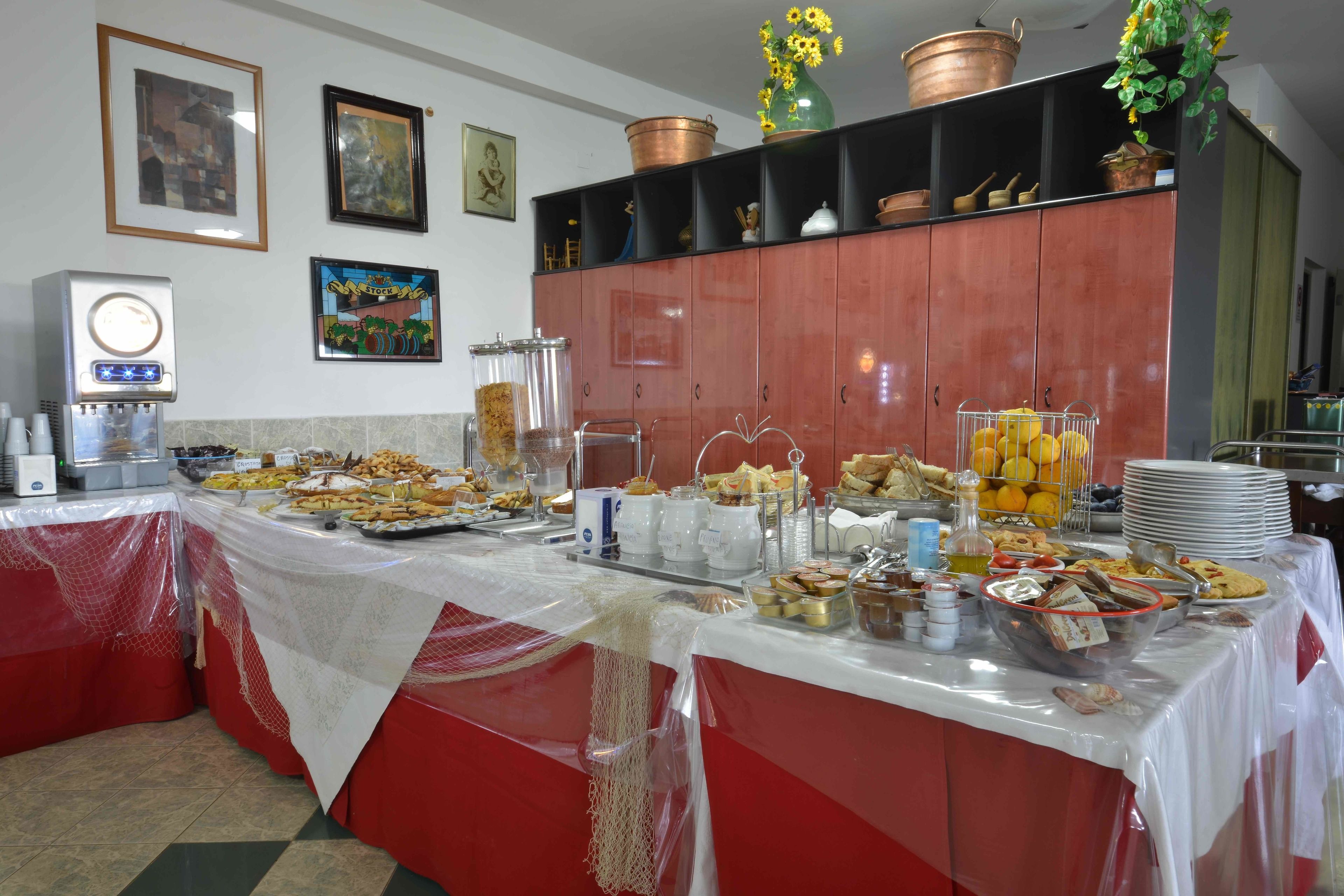 Un'impostazione per buffet con diversi cibi e bevande, una macchina per caffè e oggetti decorativi su mensole.