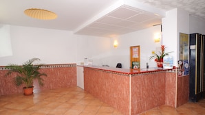 A reception area with a marble counter, a potted plant, and a tiled floor. - Hostal Montaña (Sant Antoni de Portmany)