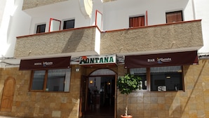 A multi-story hotel with a sign reading "MONTANA HOSTAL" and a "BAR MONTANA" sign below. - Hostal Montaña (Sant Antoni de Portmany)