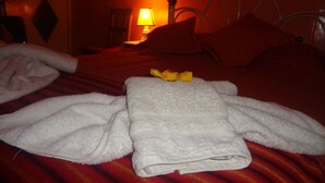 Una cama bien hecha con una colcha a rayas rojas y blancas, una toalla blanca y una toalla doblada encima.