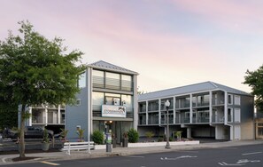A two-story building with a sign reading 'crosswinds' and 'rehoboth beach' indicating a hotel. There are parking spaces in front, a bench, and potted plants. - Crosswinds Rehoboth  (Rehoboth Beach)
