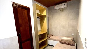 Ein Schlafzimmer mit einem Bett, einer Holztür, einem Kleiderschrank und einer Regalwand.