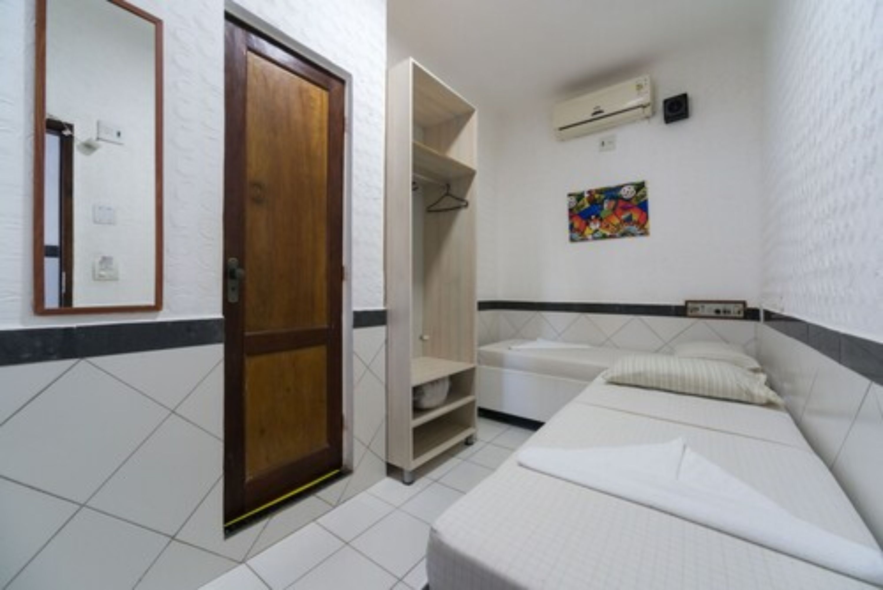 Una habitación pequeña y limpia, con cama, armario y zona de ducha.