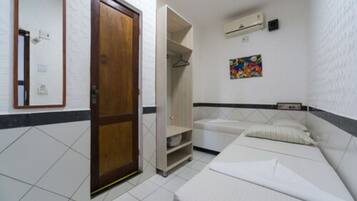 Una habitación pequeña y limpia, con cama, armario y zona de ducha.