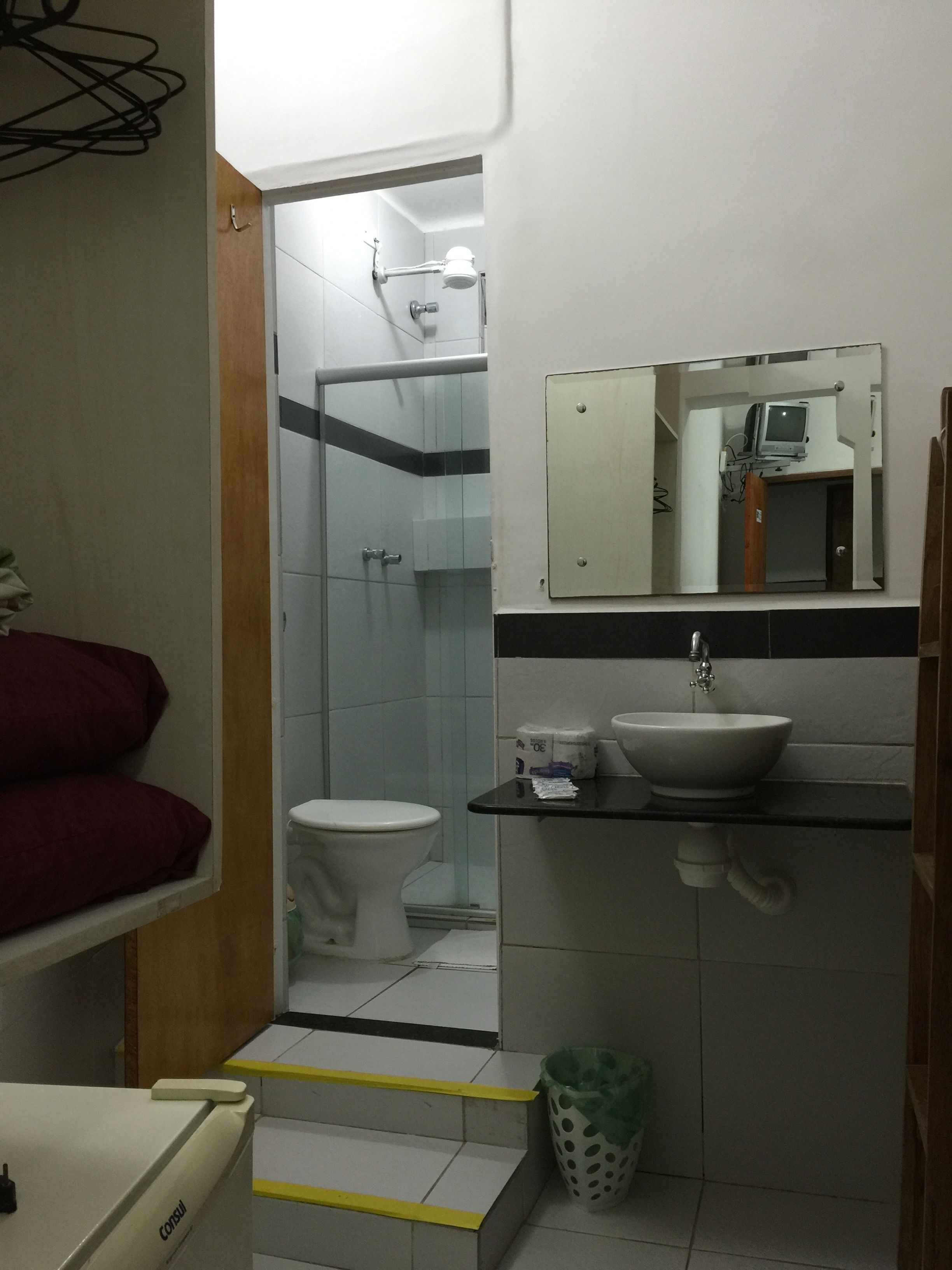 A compact bathroom with a toilet, sink, and shower.