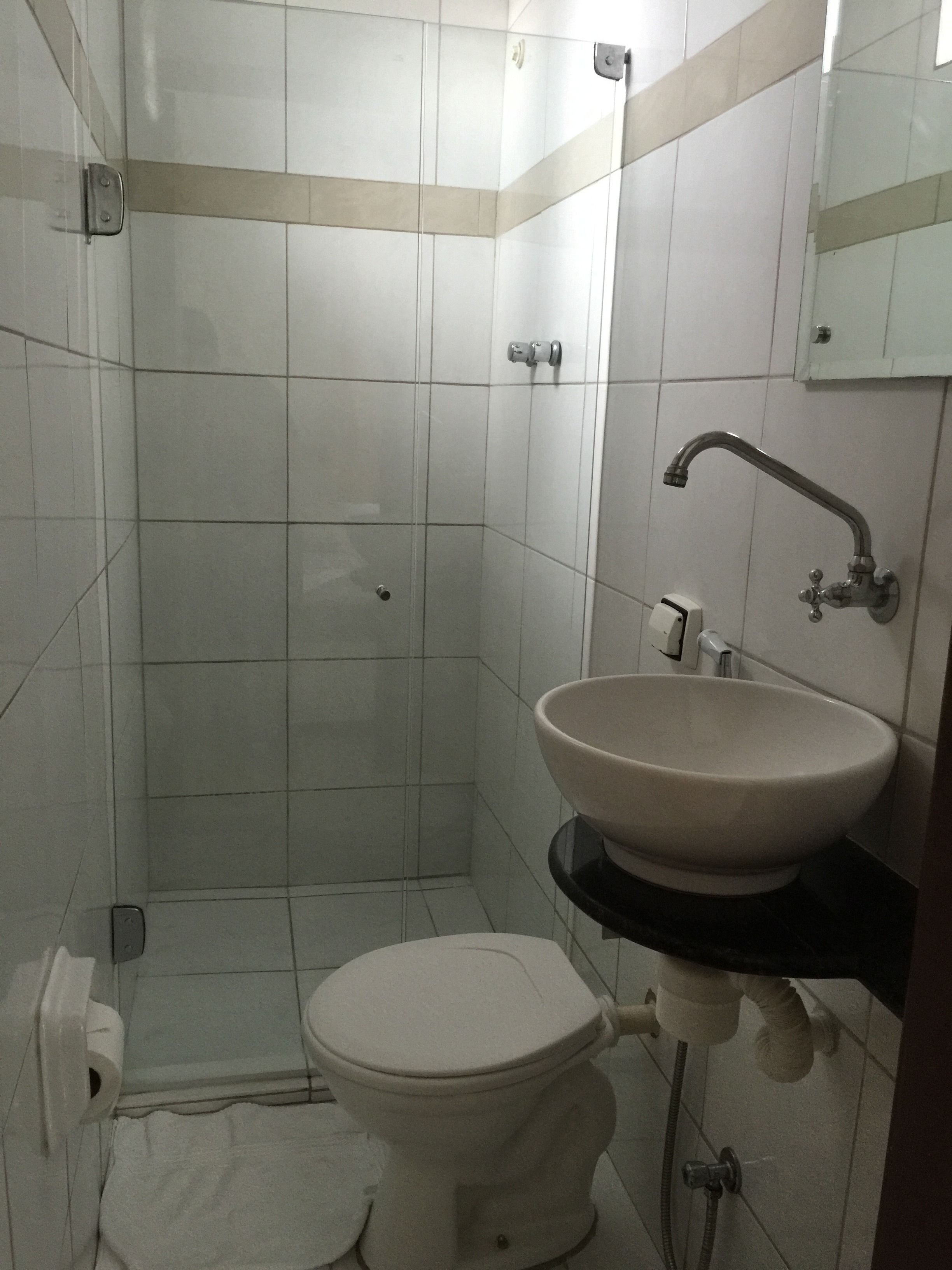 Un baño pequeño con azulejos, un inodoro, un lavamanos y una ducha.