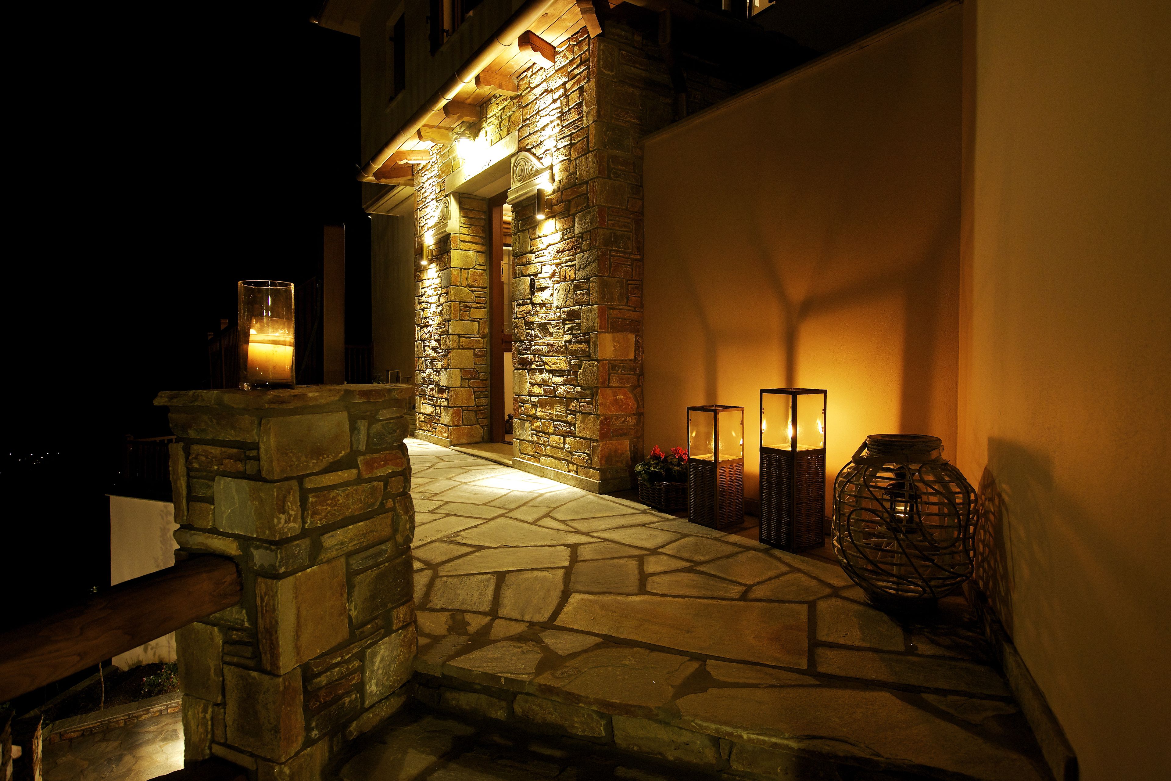 A stone staircase leading to a building entrance, illuminated by wall-mounted lights.