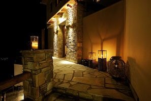 A stone staircase leading to a building entrance, illuminated by wall-mounted lights. - Lions Nine (Zagora-Mouresi)