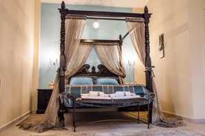 A four-poster canopy bed with a dark wooden frame, blue bedding, and beige drapes. - Lions Nine (Zagora-Mouresi)