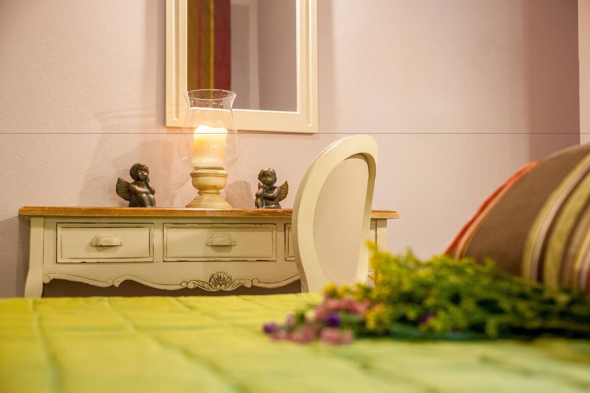 A bedroom with a bed, a bedside table with a lamp, and a mirror on the wall.