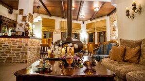 A cozy interior with a stone wall, wooden ceiling, and a bar area with bottles and glasses. - Lions Nine (Zagora-Mouresi)