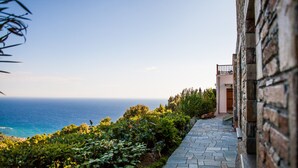 A stone pathway leading to a building with a view of the sea. - Lions Nine (Zagora-Mouresi)