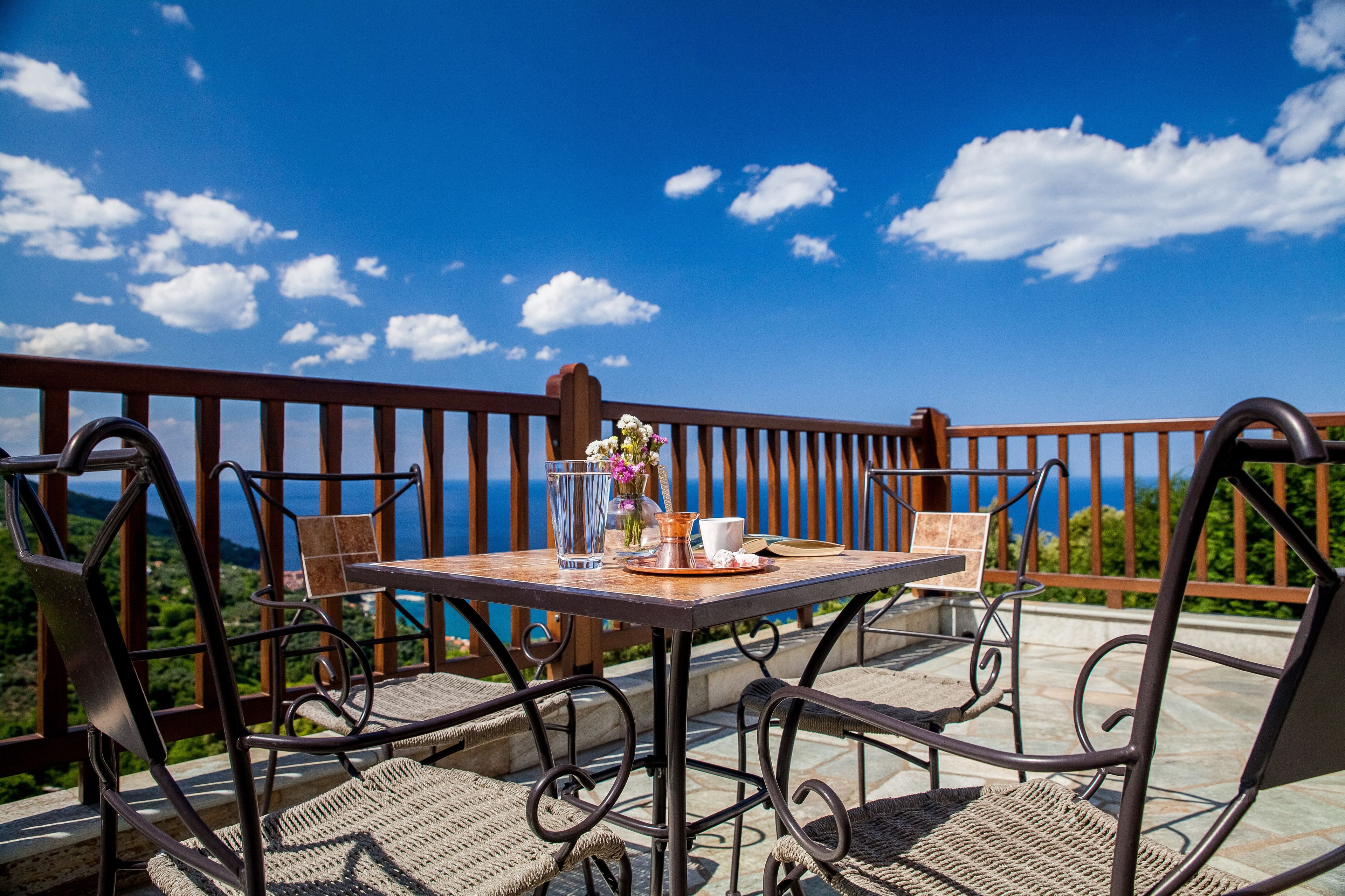 A table with chairs on a balcony overlooking a scenic landscape.