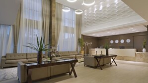 Un vestíbulo amplio con mostrador de recepción, sofás y una mesa de centro.