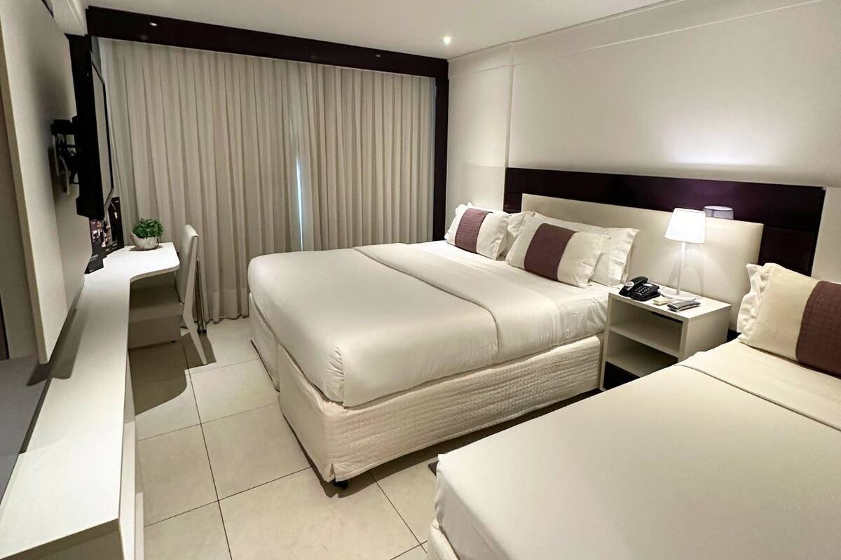 Een hotelkamer met een groot bed, een nachtkastje met een lamp en een bureau met een stoel.