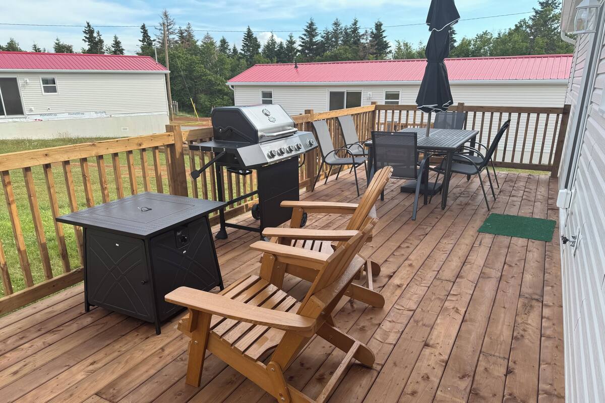 A wooden deck with a grill, a table, and chairs.