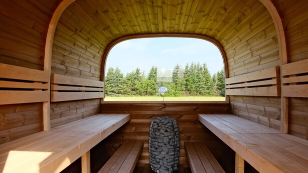 Una sauna con bancos de madera y una pared de piedra en el centro.