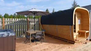 Un jacuzzi, una terraza de madera y una sauna con revestimiento de madera curva.