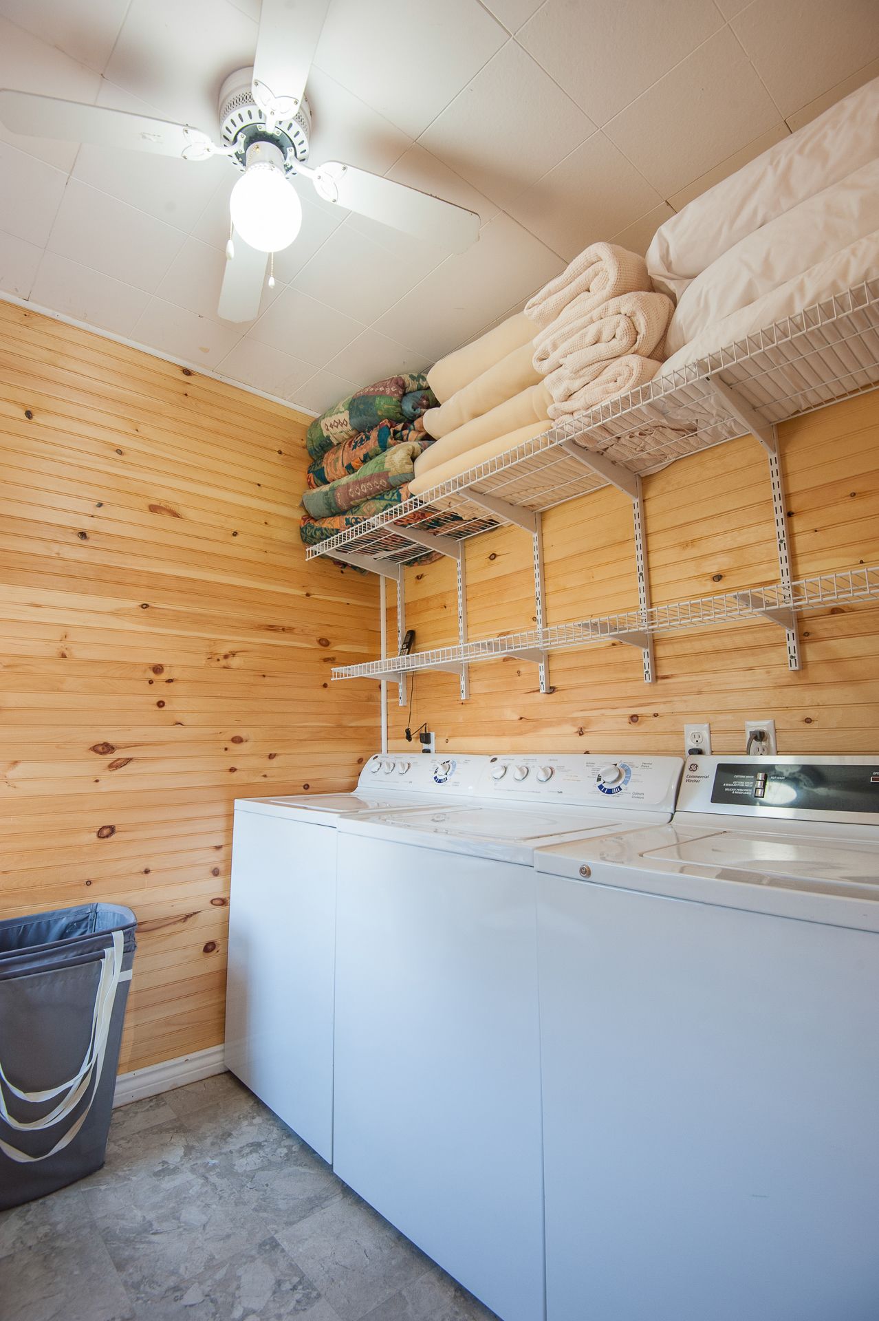 A laundry room with a washing machine, dryer, and shelves for folded towels.