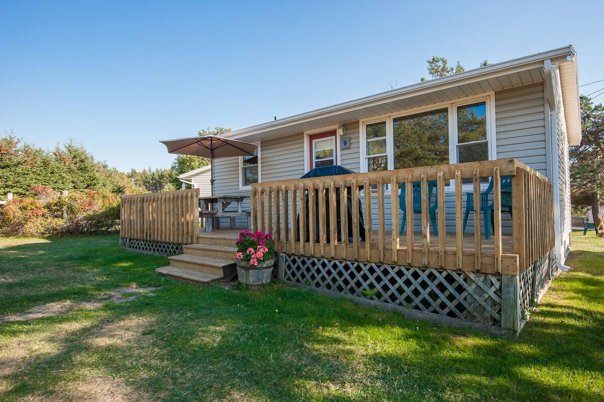 A two-story house with a wooden deck and a covered patio area.