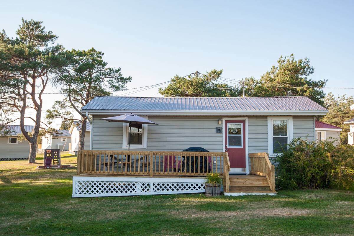 A single-story house with a red door, a covered porch, and a small front yard.