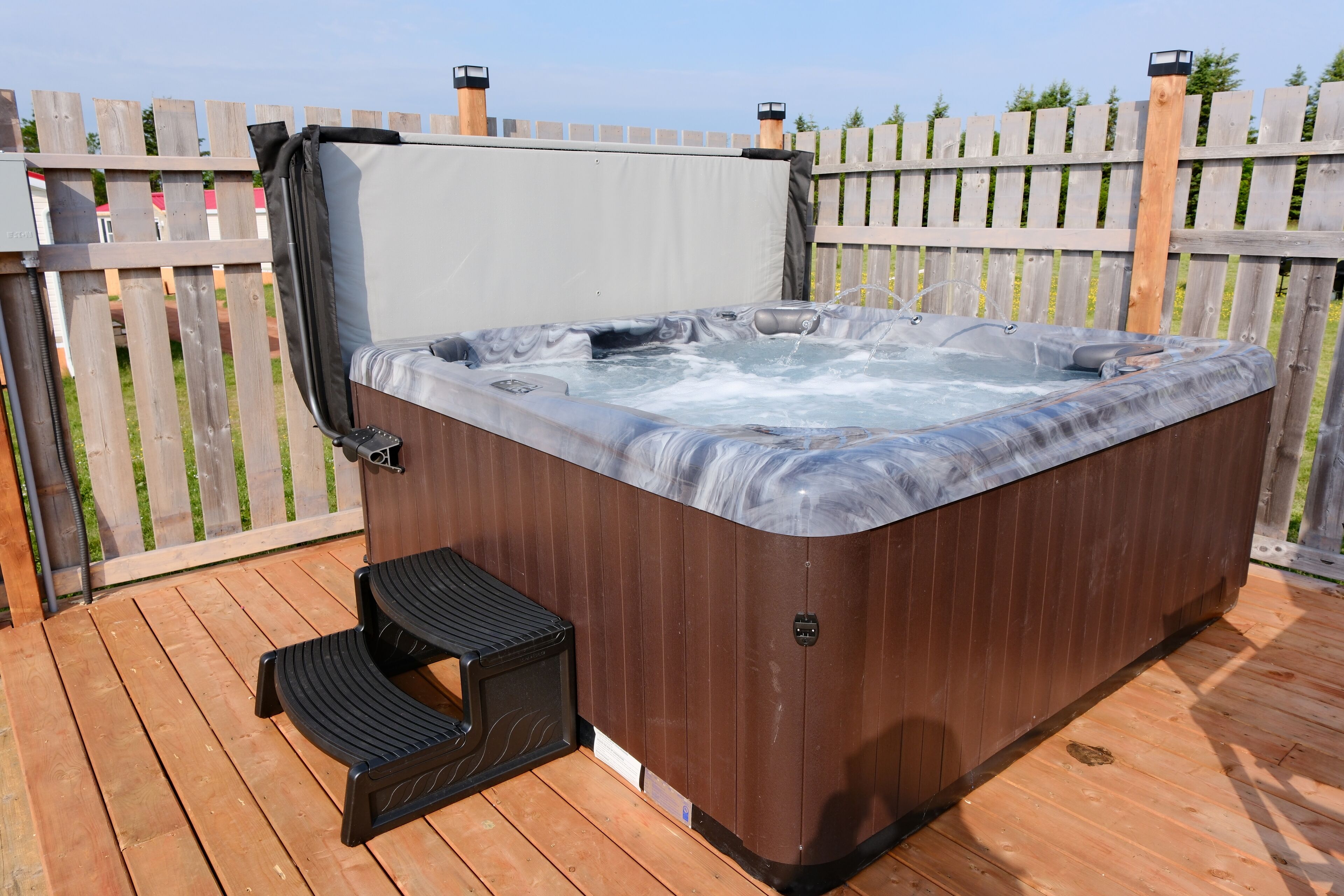 Ein Whirlpool auf einer Holzterrasse mit einem Holzzaun im Hintergrund.