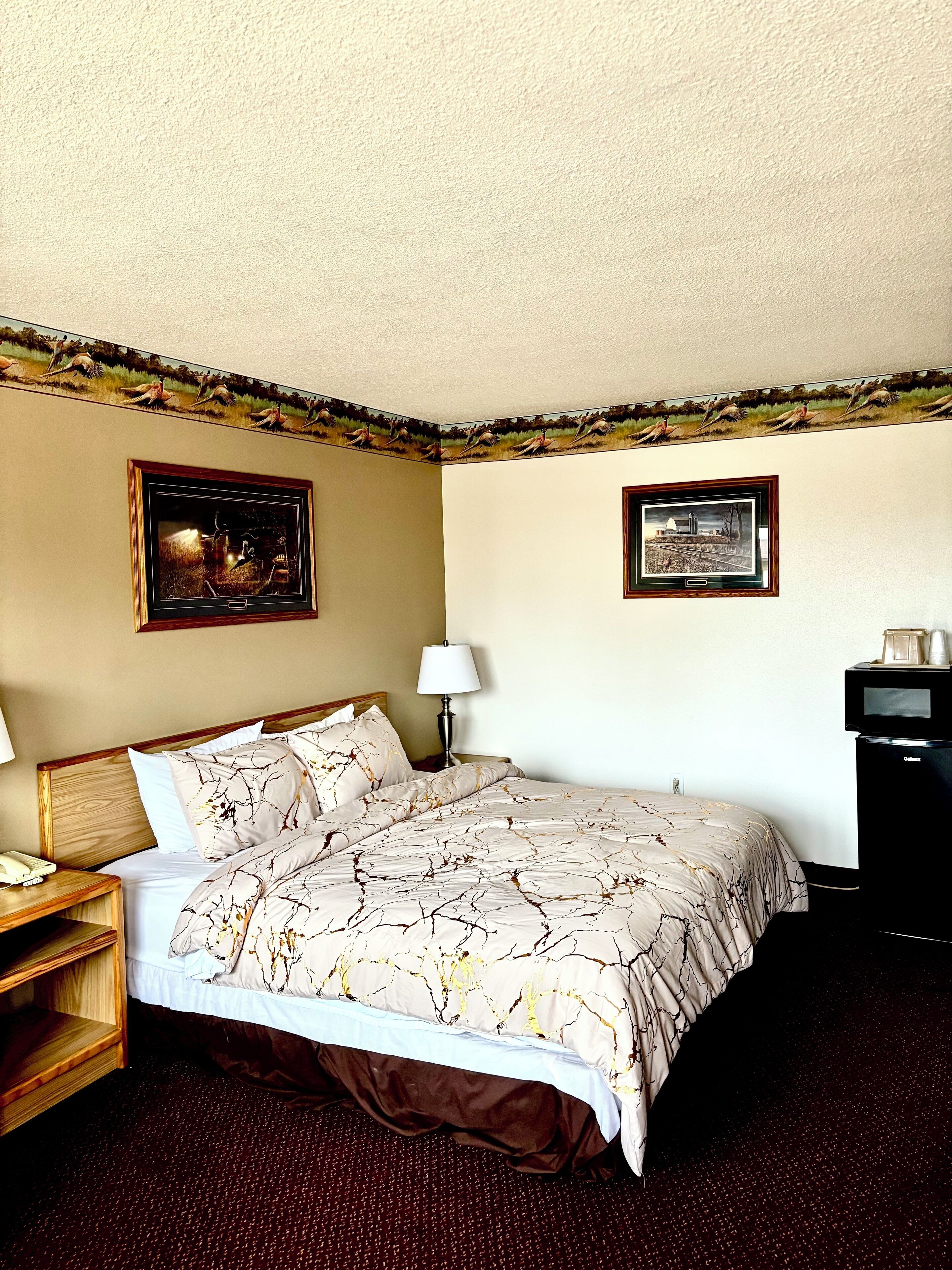 Quarto de hotel com cama, mesa de cabeceira, abajur, escrivaninha e cafeteira.
