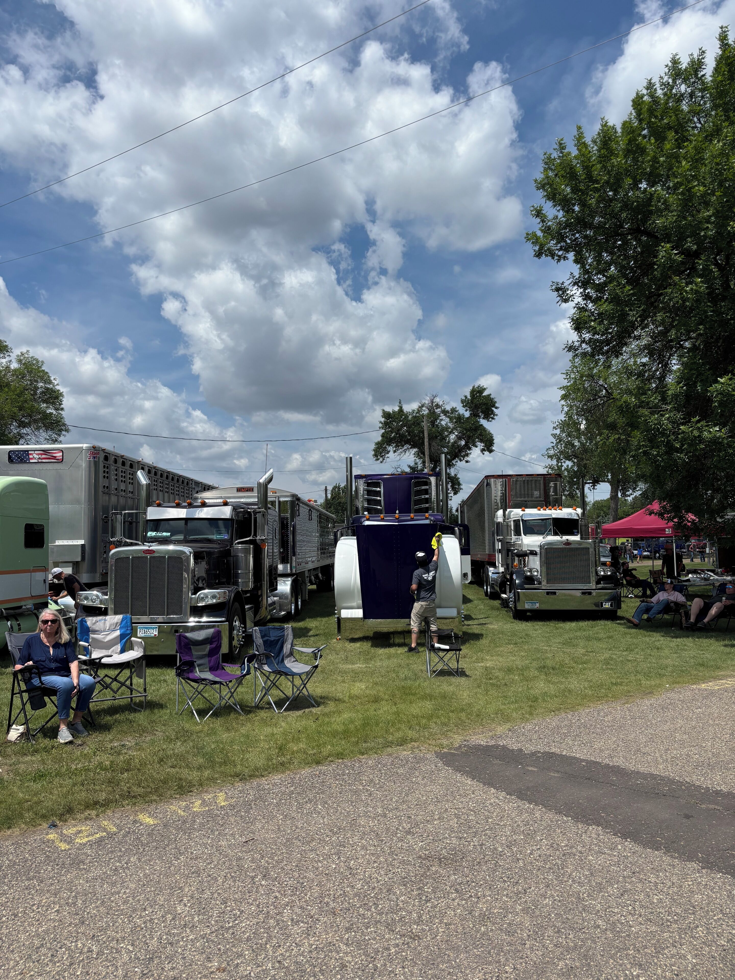 A parking lot with several large trucks and trailers, some with American flags.