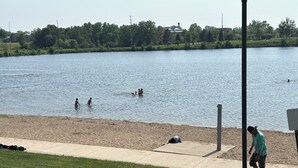 Un parque junto al lago con arena y césped.