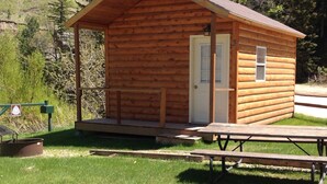 Eine kleine Holzhütte mit Veranda, Tür und einem Picknicktisch davor.