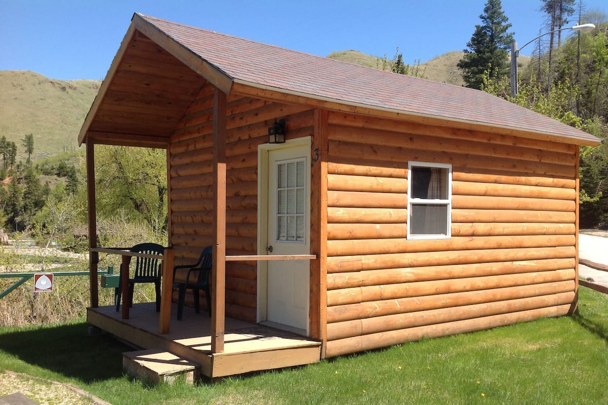 Une petite cabane en bois avec une véranda, une porte et une fenêtre.